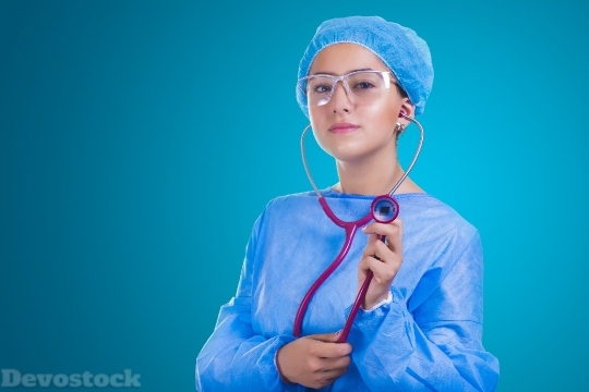 Devostock FEMALE DOCTOR PUTTING STETHOSCOPE IN THE EAR IN SURGICAL CLOTHES