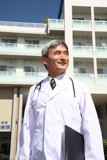 Devostock MALE DOCTOR STANDING IN FRONT OF HOSPITAL
