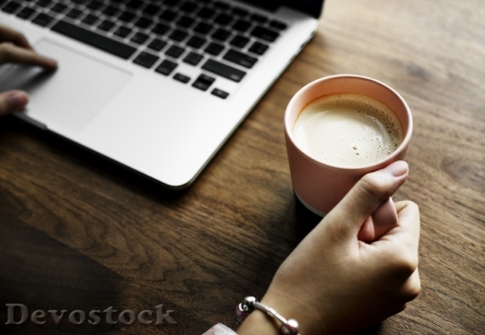 Devostock A cup of nice hot milk next to a computer laptop