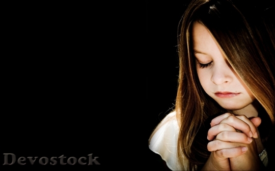 Devostock A little girl praying while her eyes are closed