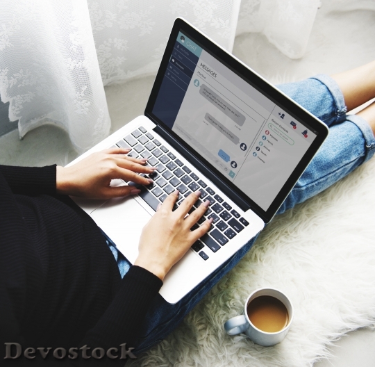 Devostock A Woman Sitting on the Floor and Using Laptop