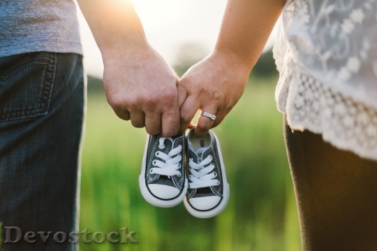 Devostock Couple expecting a child and holding little shoe