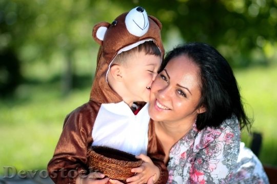 Devostock Little boy wearing bear costume kissing his mom