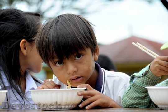 Devostock Poor child eating noodles