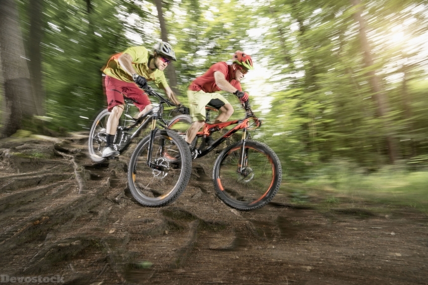 Devostock two mountainbikers riding over roots in forest