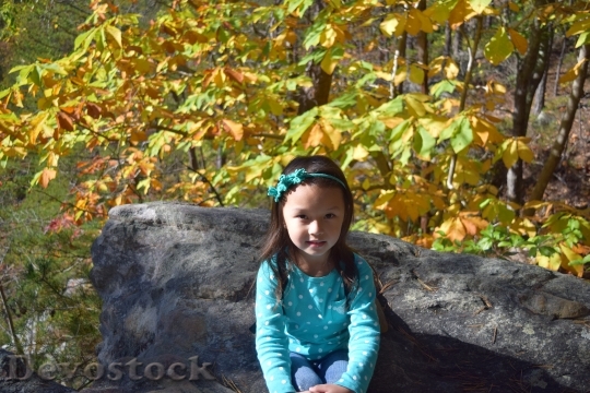 Devostock Smiling Girl Autumn Leaves